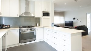 A modern kitchen with white cabinetry, a built-in stove, and a microwave. - Rsl Club Motel (Wagga Wagga)