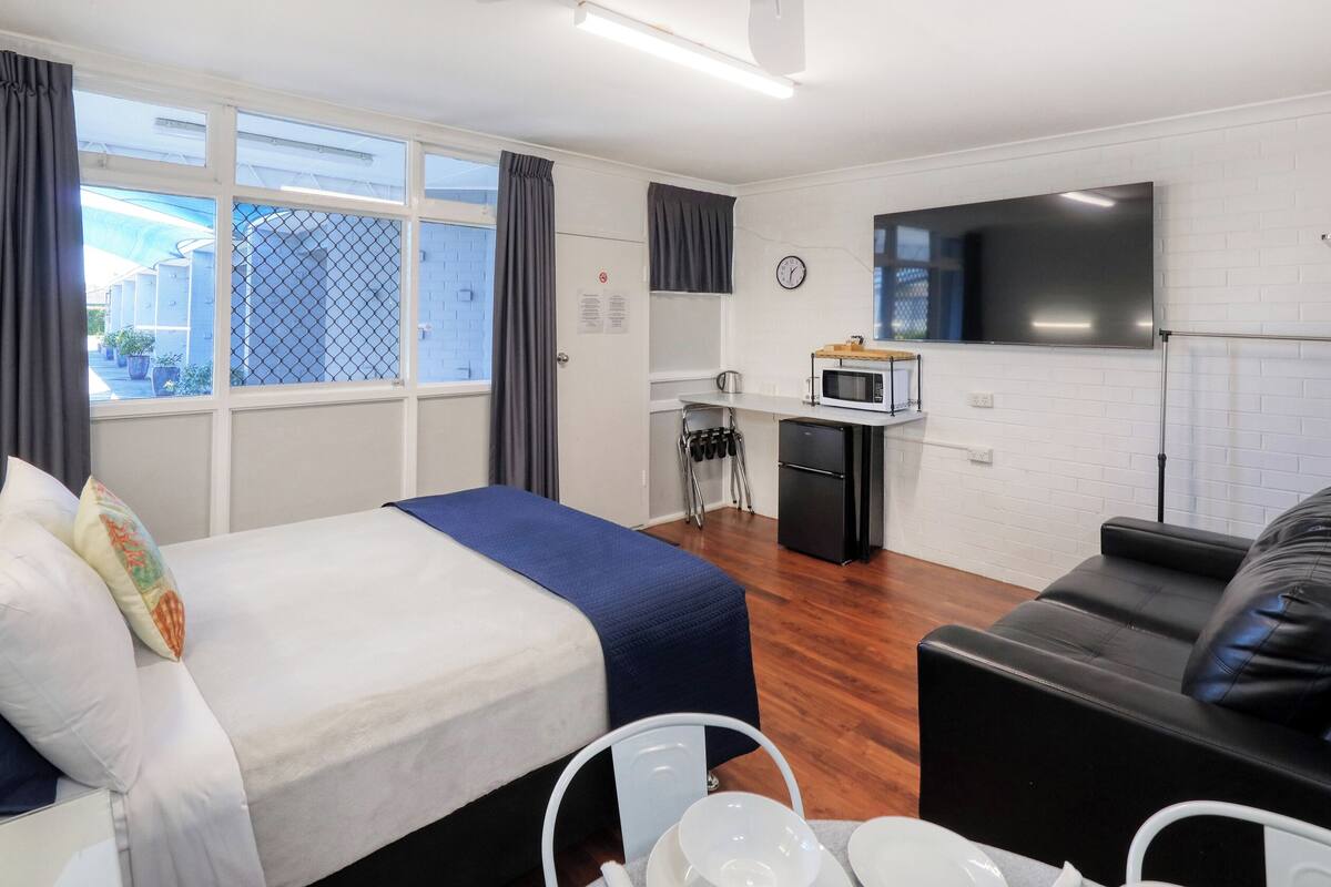 Ein Hotelzimmer mit Bett, einer Couch, einem Esstisch, einer Mikrowelle und einem Fernseher.