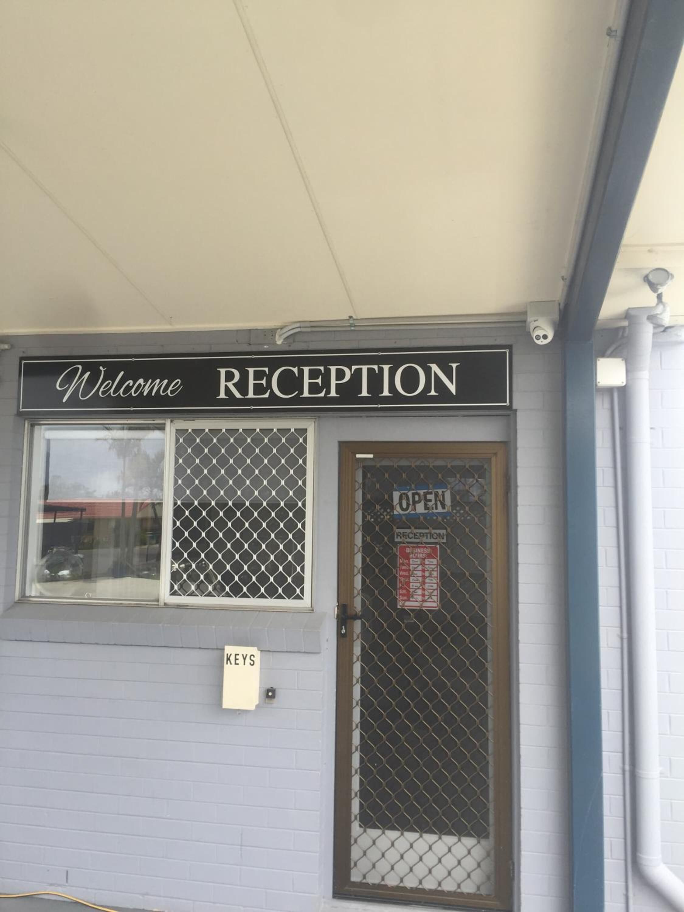 Un área de recepción con un cartel que dice 'Welcome' sobre la puerta, un cartel con la palabra 'Keys' debajo de la puerta y un cartel de 'Reception' en la puerta.