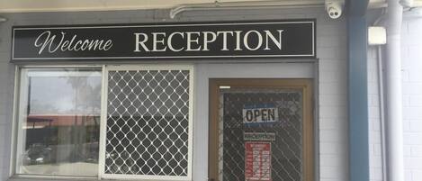 Un área de recepción con un cartel que dice 'Welcome' sobre la puerta, un cartel con la palabra 'Keys' debajo de la puerta y un cartel de 'Reception' en la puerta.