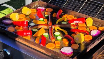 Una parrilla con diversos vegetales y salchichas a la cocción.
