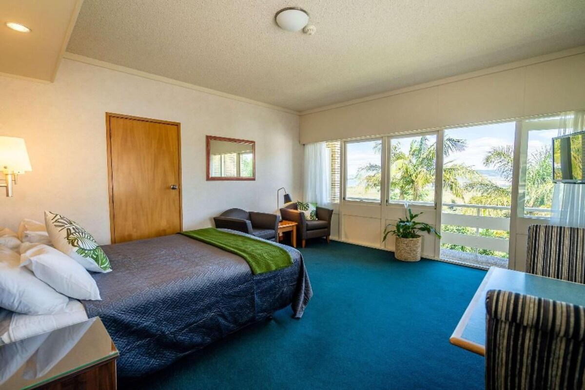 Una habitación de hotel con cama, escritorio, silla, ventana con vista y puerta.