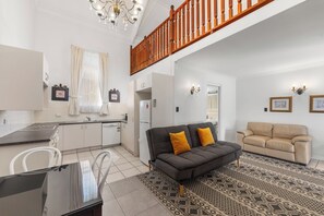 Eine moderne Küche mit weißen Schränken, einem Esstisch mit Stühlen, einem Sofa mit gelben Kissen und einem beigen Sofa.