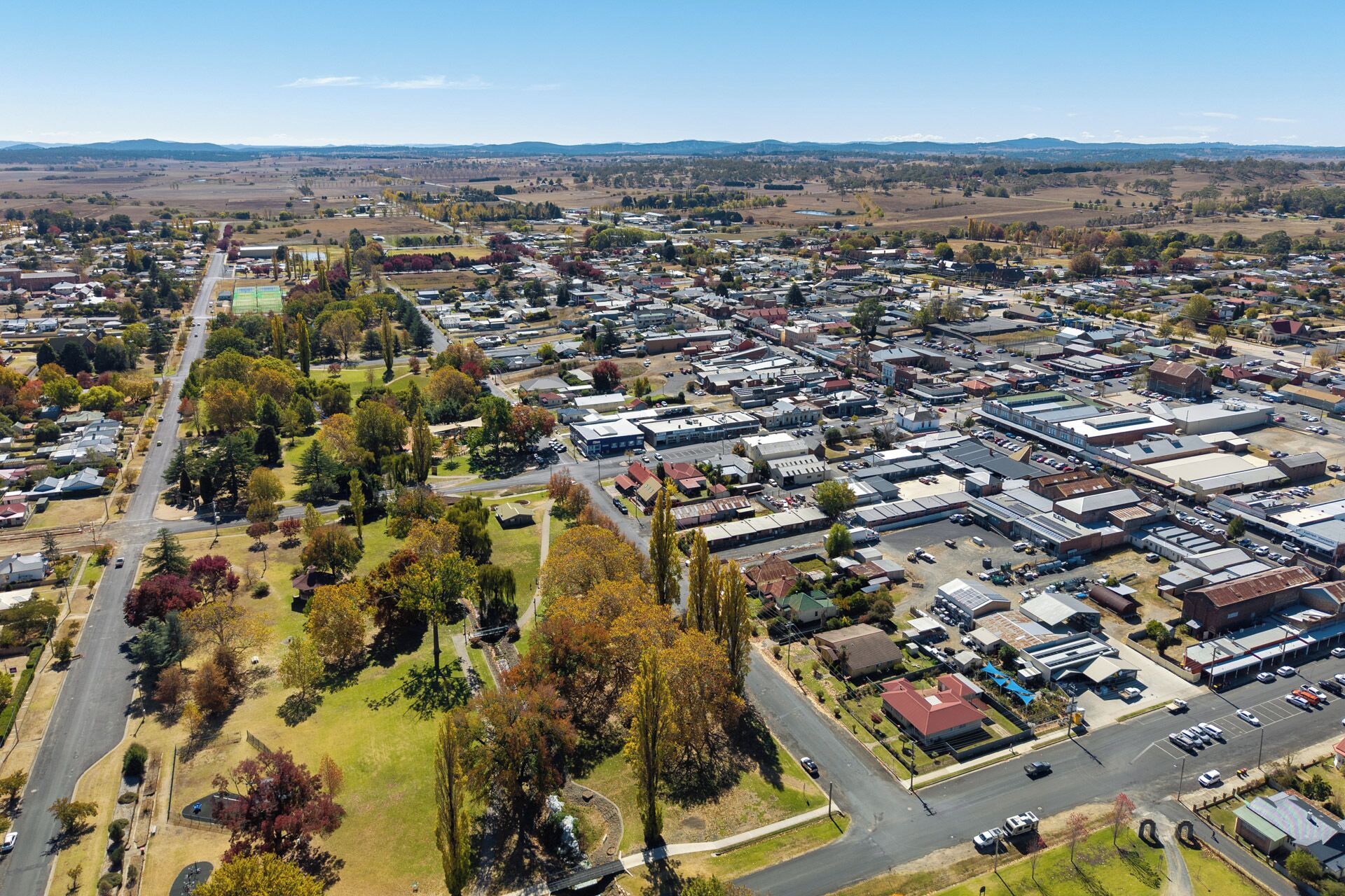 An aerial view of a town with a mix of residential and commercial buildings, roads, and green spaces.