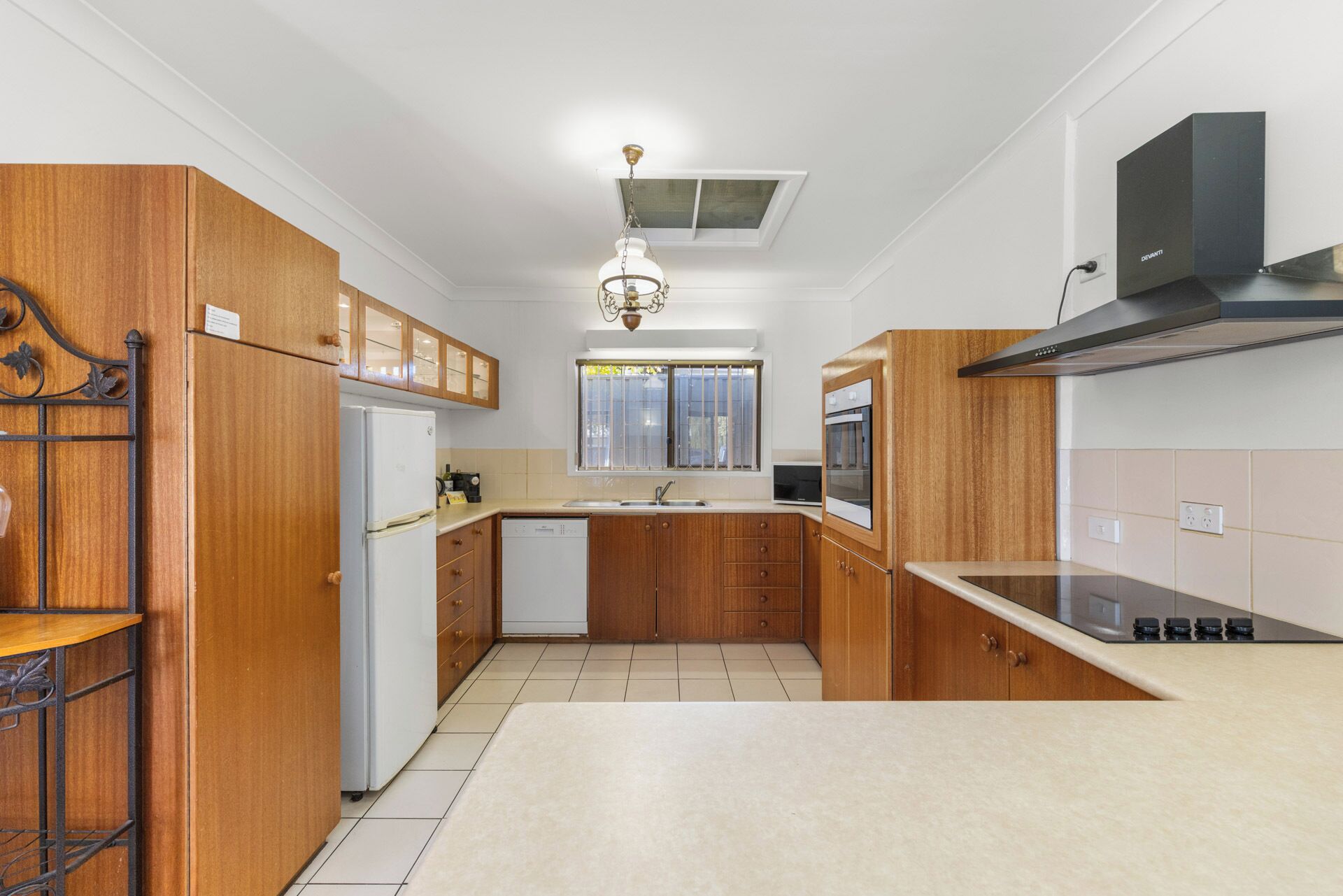 A modern kitchen with wooden cabinets, a built-in oven, a microwave, and a stainless steel range hood.