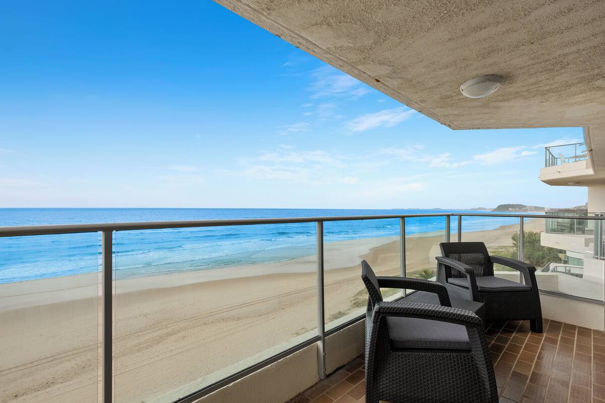 A balcony with a view of the beach and ocean.
