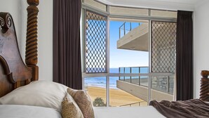 A bedroom with a large window overlooking a beach. - Foreshore Apartments (Mermaid Beach)
