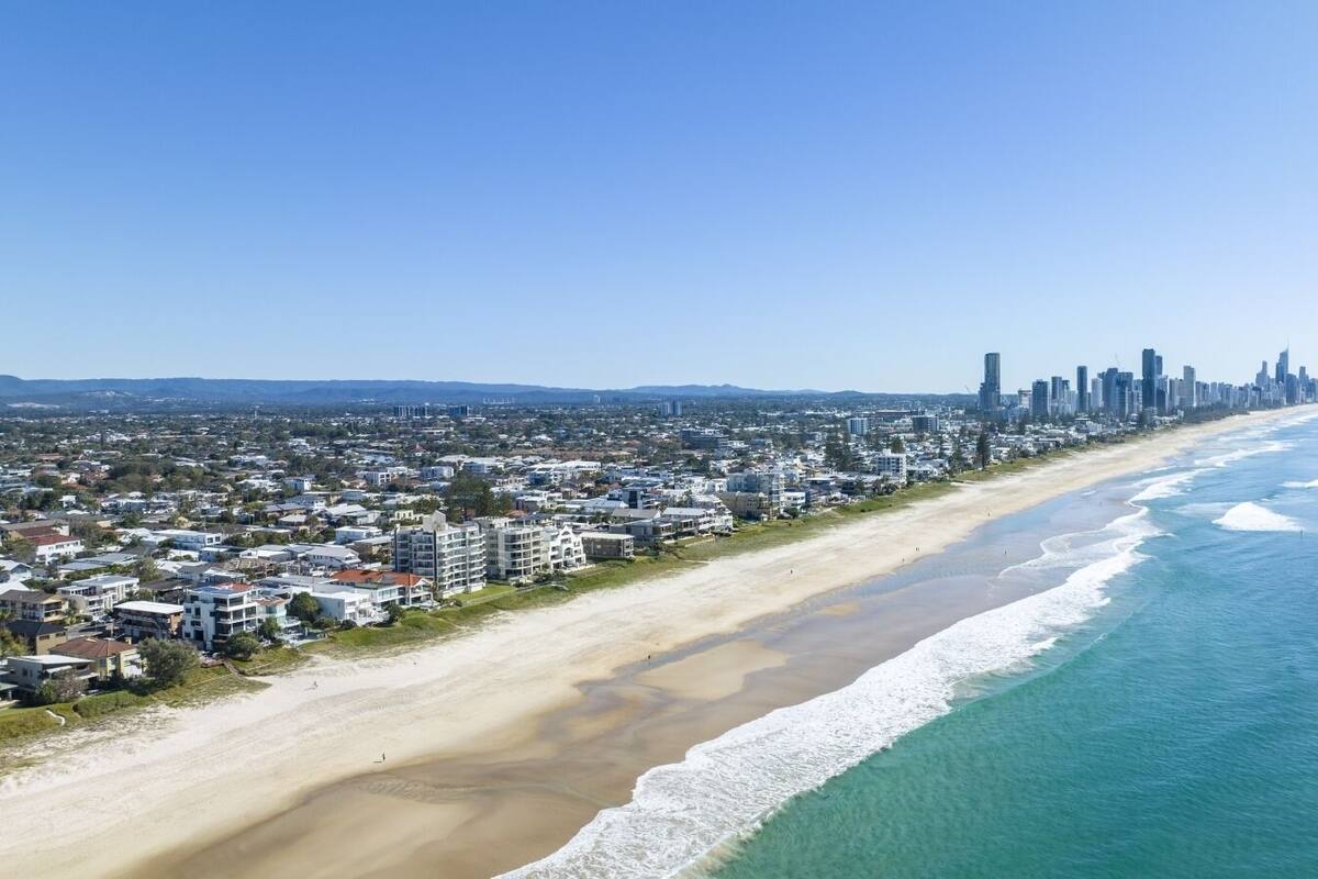 A coastal cityscape with a beachfront, buildings, and a clear sky.