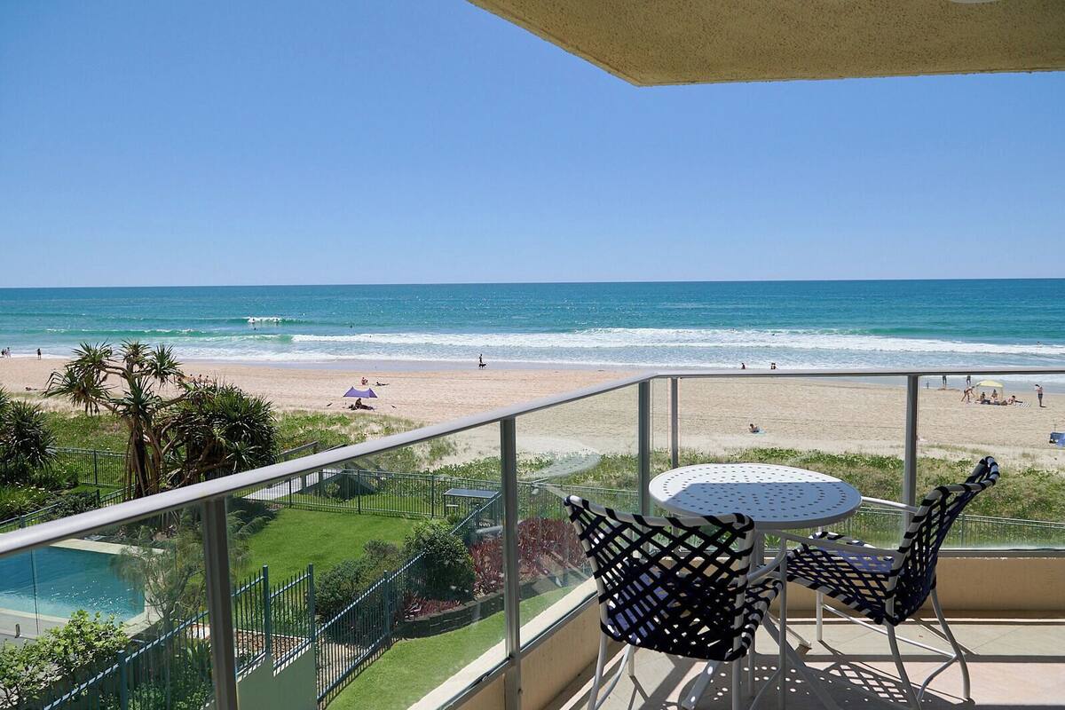 A balcony with a view of the beach and ocean.