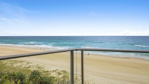 A beach view from a balcony with a railing, sandy beach, and ocean. - Foreshore Apartments (Mermaid Beach)