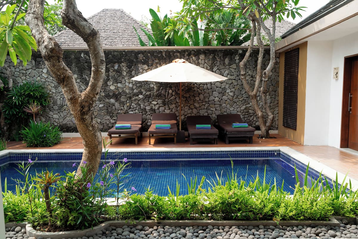A poolside area with lounge chairs, a stone wall, and a tiled pool.