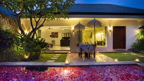 A modern house with a dining area, stone wall, and a pool with flower petals. - The Yubi Boutique Villas Seminyak (Seminyak)