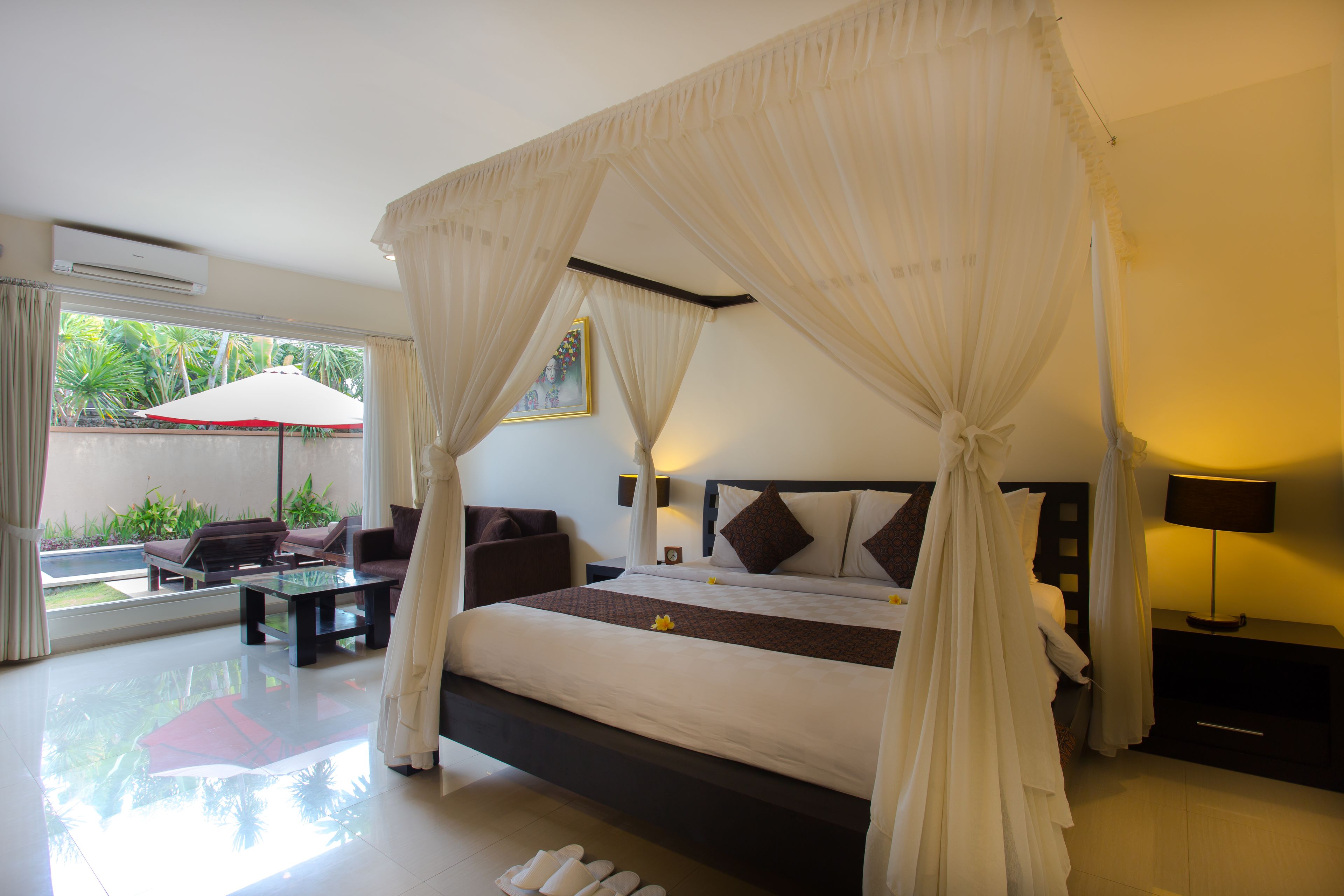A spacious bedroom with a large bed, a sitting area with a table and chairs, and a view of the outdoors.