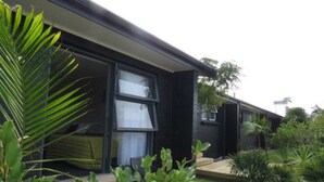 Ein modernes Haus mit dunkler Fassade, großen Fenstern und einem gepflegten Garten mit verschiedenen Pflanzen.