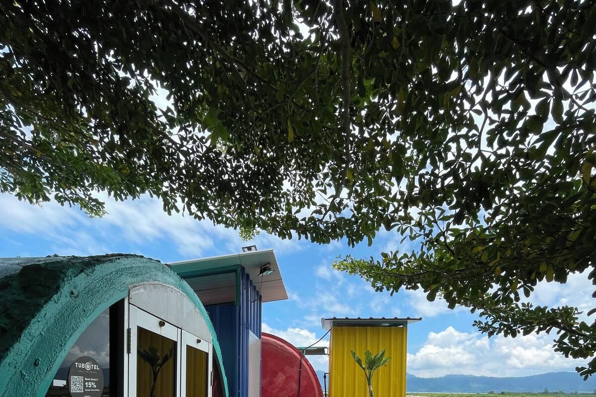 A colorful outdoor deck with a glass enclosure, a red slide, and a yellow structure with a plant.