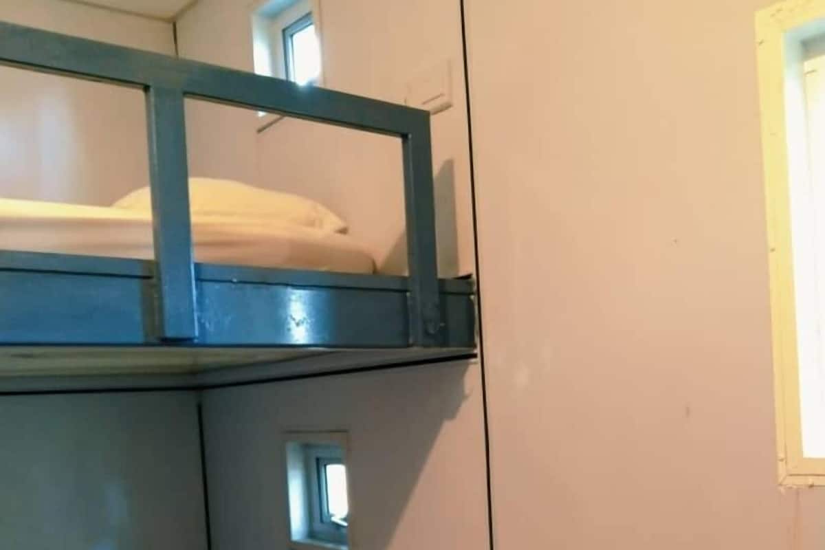 A bunk bed with a window, a single bed, and a wall-mounted heater.