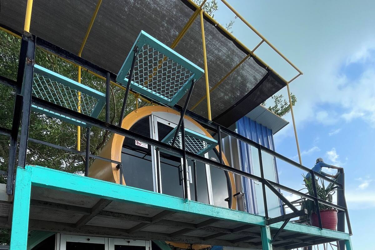 A two-story building with a balcony, a potted plant, and a sign indicating a 15% discount.