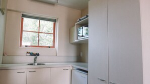Eine Küche mit Fenster, weißen Schränken und einem eingebauten Geschirrspüler.