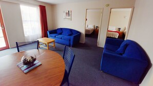 Ein Zimmer mit einem Holzespeisetisch, blauen Sofas und einem kleinen Tisch mit einer Glasglocke als Mittelpunkt.