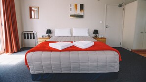 Ein Hotelzimmer mit einem großen Bett, zwei Nachttischen mit Lampen, einem Kleiderschrank, einem Spiegel und einem Bild an der Wand.