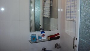 Ein Badezimmer mit einer Glasablage für Pflegeprodukte, einem Spiegel und einem Handtuchhalter.