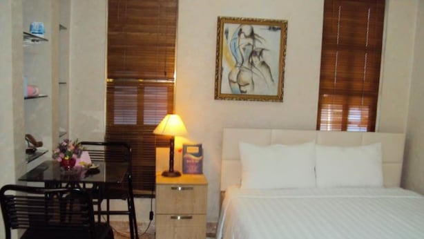 Ein Hotelzimmer mit Bett, Schreibtisch mit Stuhl, Lampe und einem Bild an der Wand.
