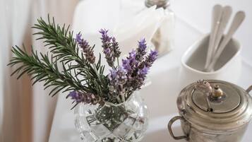 A table with a glass vase of lavender, a salt and pepper shaker set, a white napkin, and a teapot.