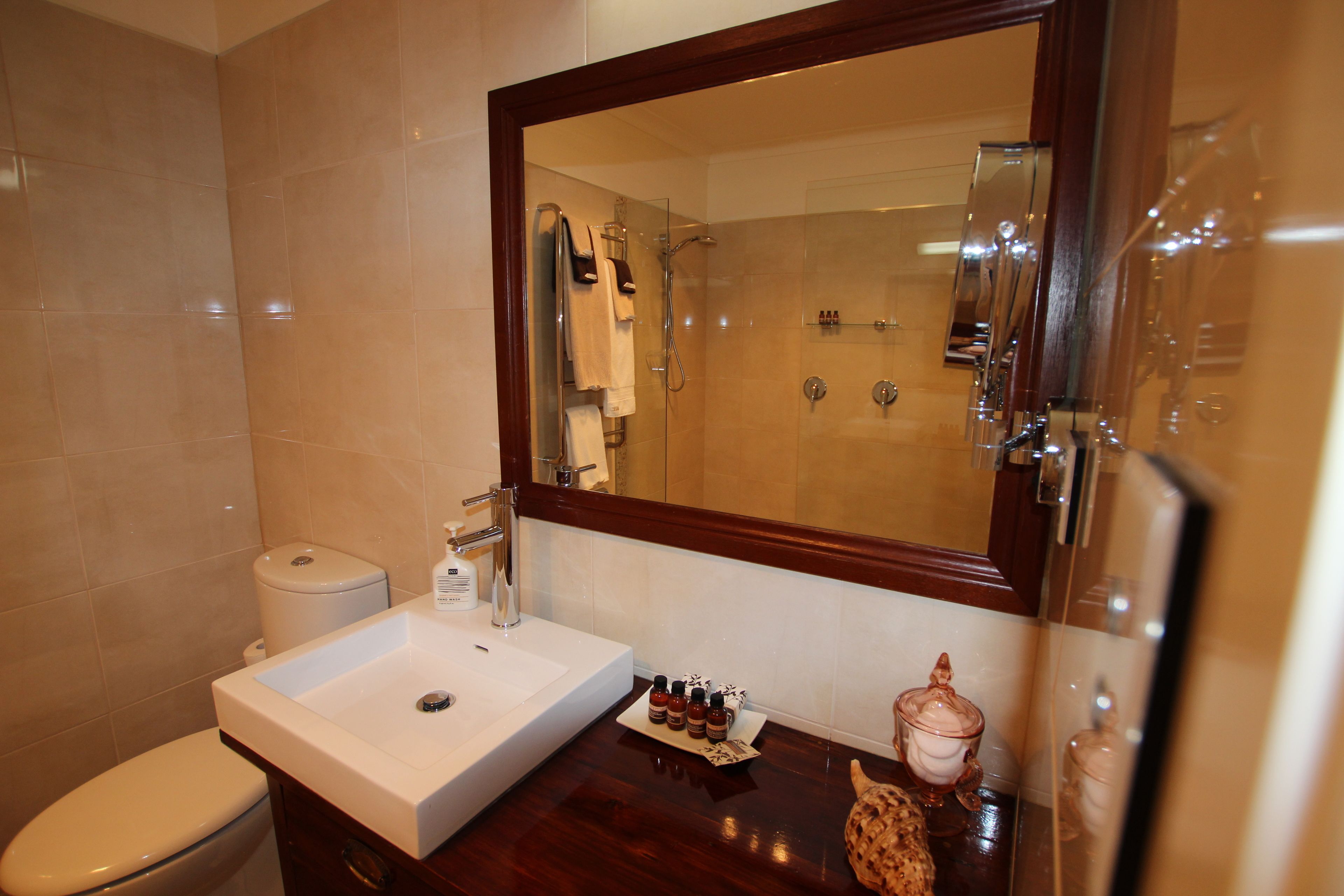 Un baño con lavamanos blanco, espejo, inodoro y zona de ducha.