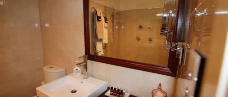 Un baño con lavamanos blanco, espejo, inodoro y zona de ducha.