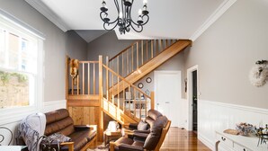 A spacious living room with a wooden staircase, leather furniture, and a chandelier. - The Ark Stanley (Stanley)