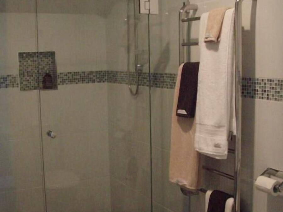 A glass-enclosed shower area with a towel rack holding multiple towels.