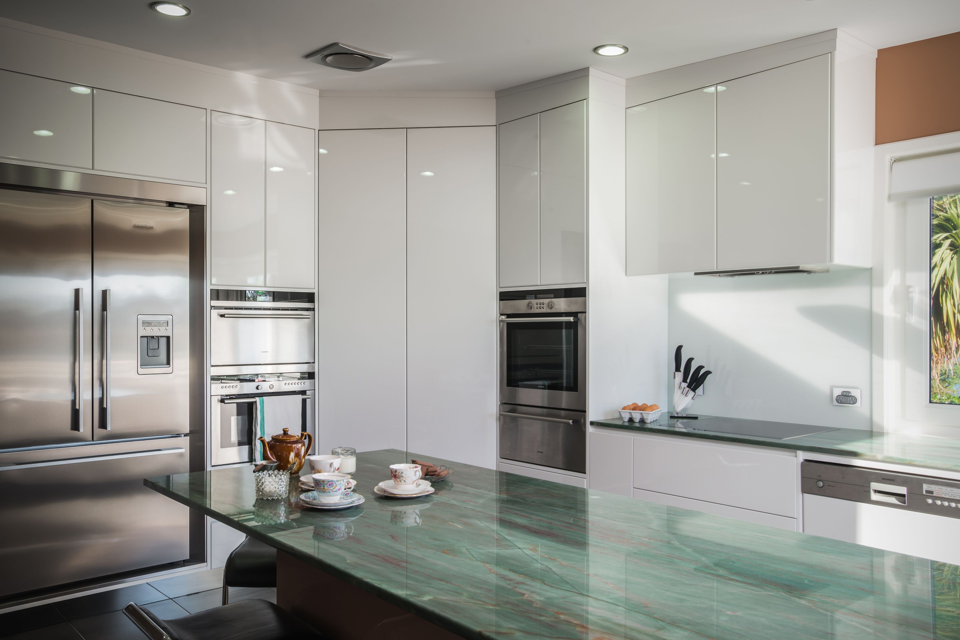 A modern kitchen with stainless steel appliances, a glass-top island, and white cabinetry.