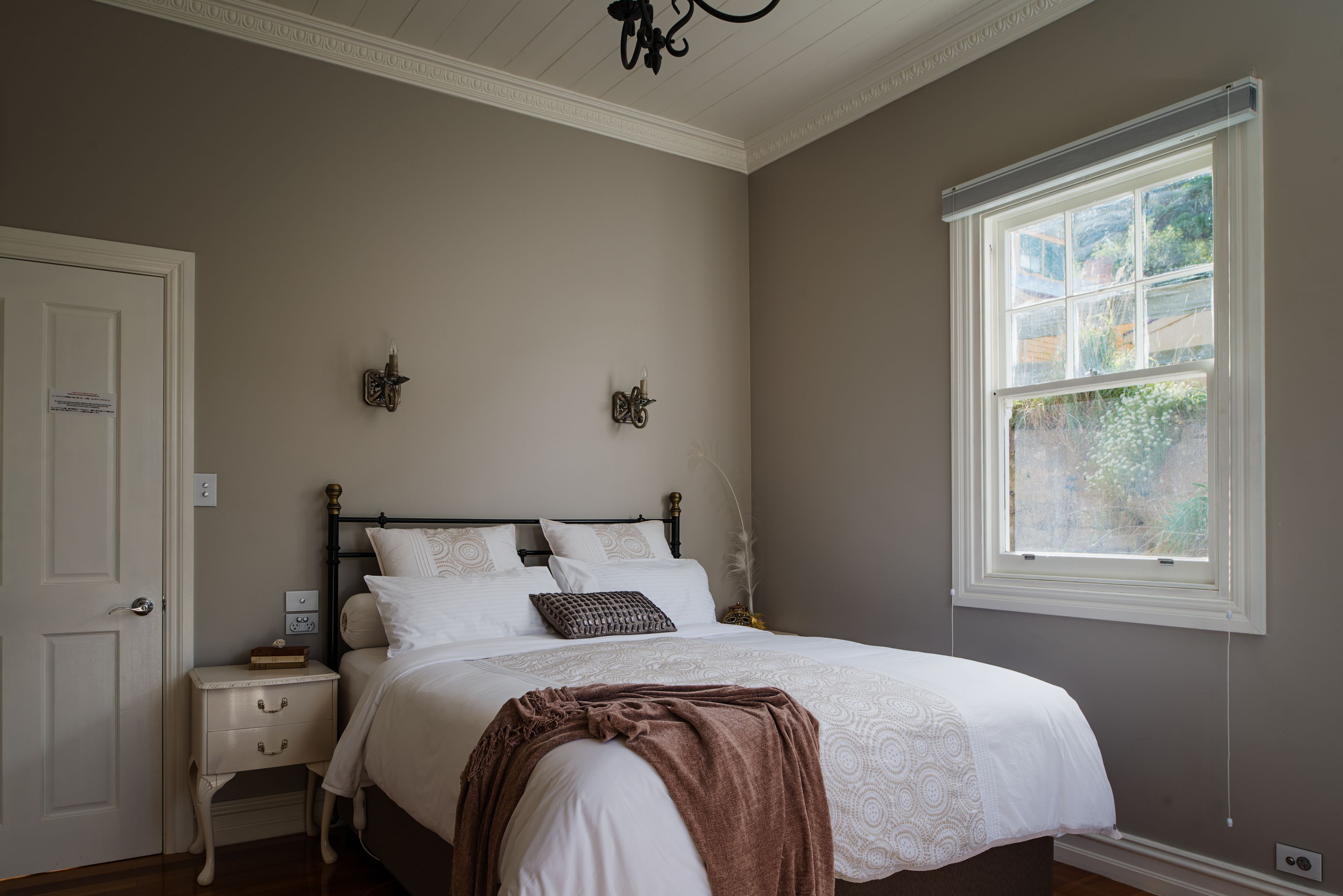 Quarto com cama, mesa de cabeceira e janela.