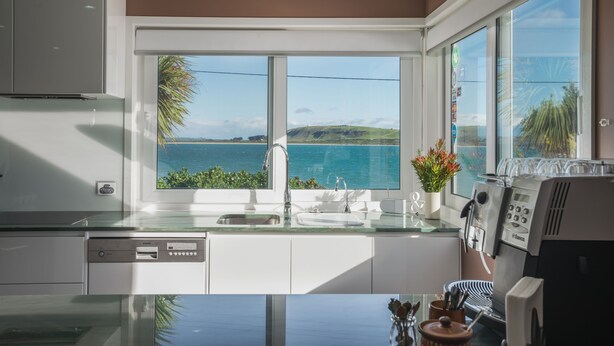 A modern kitchen with a large window offering a view of the sea and hills. - The Ark Stanley (Stanley)