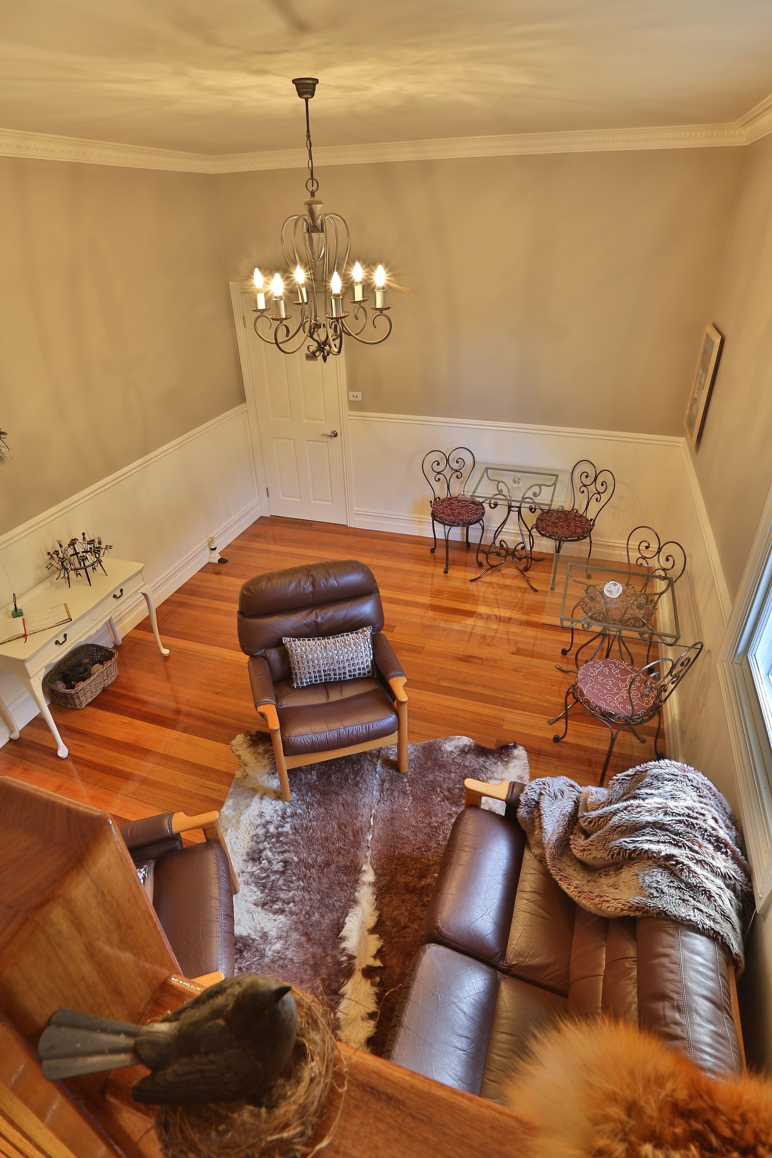 A cozy living room with a brown leather sofa, a chandelier, and a white door.