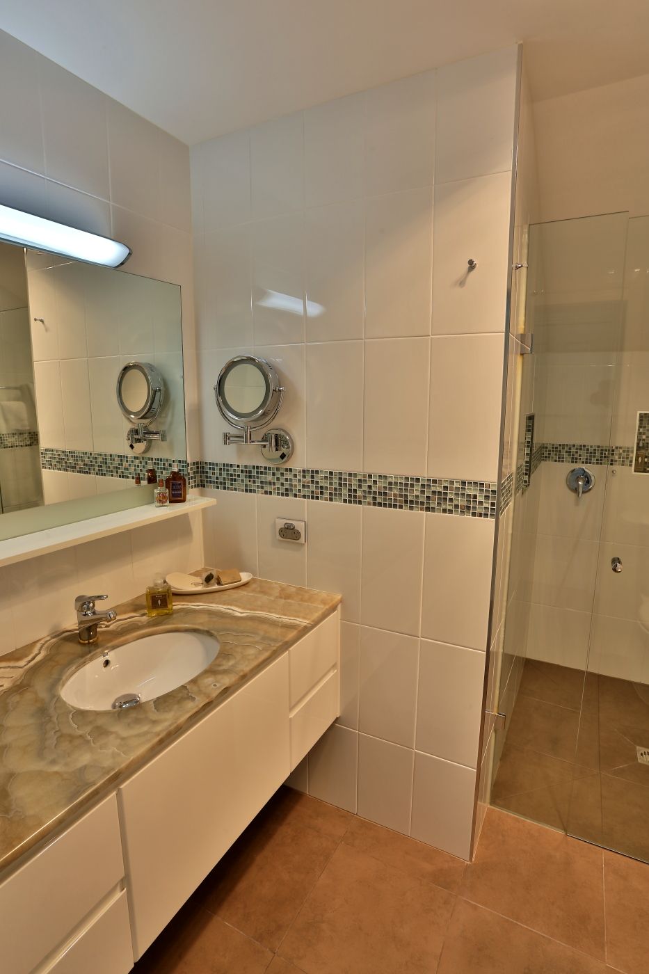 A bathroom with two sinks, a mirror, and a shower.