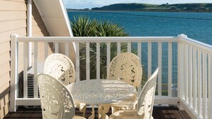 A white outdoor seating area with a table and chairs, overlooking a body of water and hills. - The Ark Stanley (Stanley)