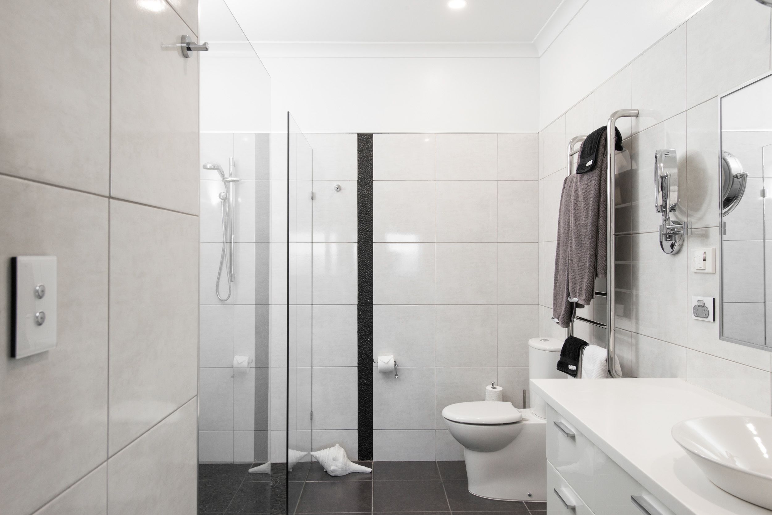 A modern bathroom with a glass shower enclosure, a toilet, and a white sink with a mirror.