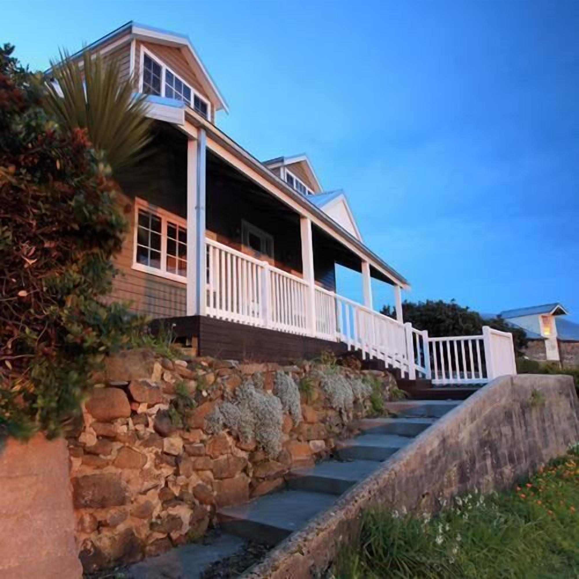 A two-story house with a stone retaining wall and a wooden deck.