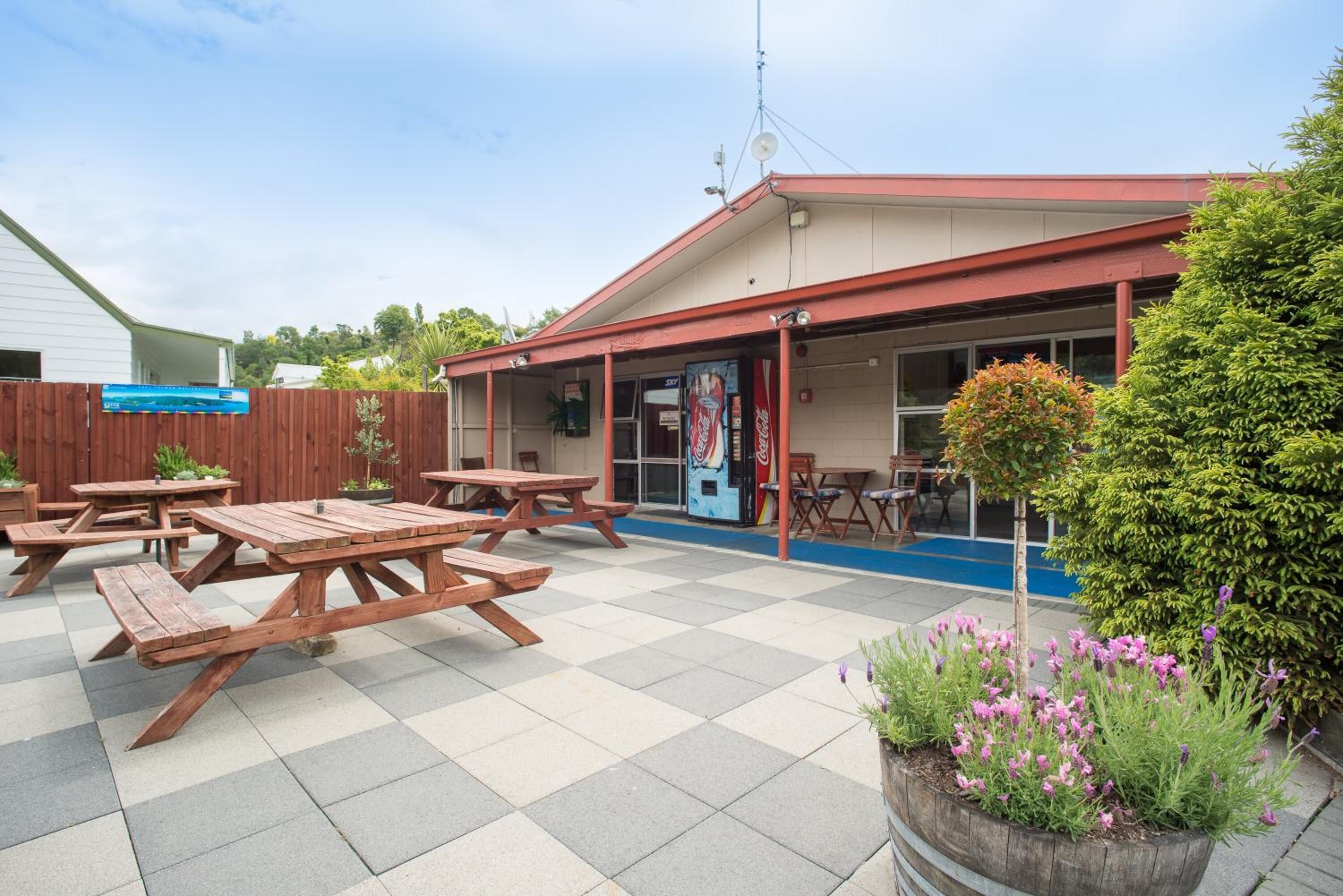 Un área de patio exterior con mesas de picnic y una máquina expendedora de Coca-Cola.