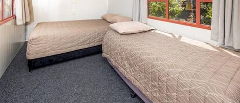 Una habitación con dos camas, un ventanal con vistas a zonas verdes y suelo alfombrado.