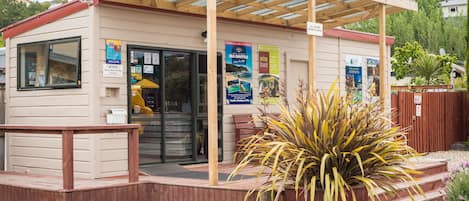 A small, single-story building with a wooden deck and a covered area. There are multiple signs advertising local attractions and services.