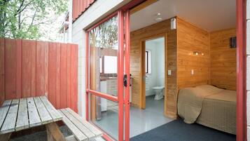 Una cabaña de madera con una puerta corredera de vidrio que da a un baño y un dormitorio pequeño.