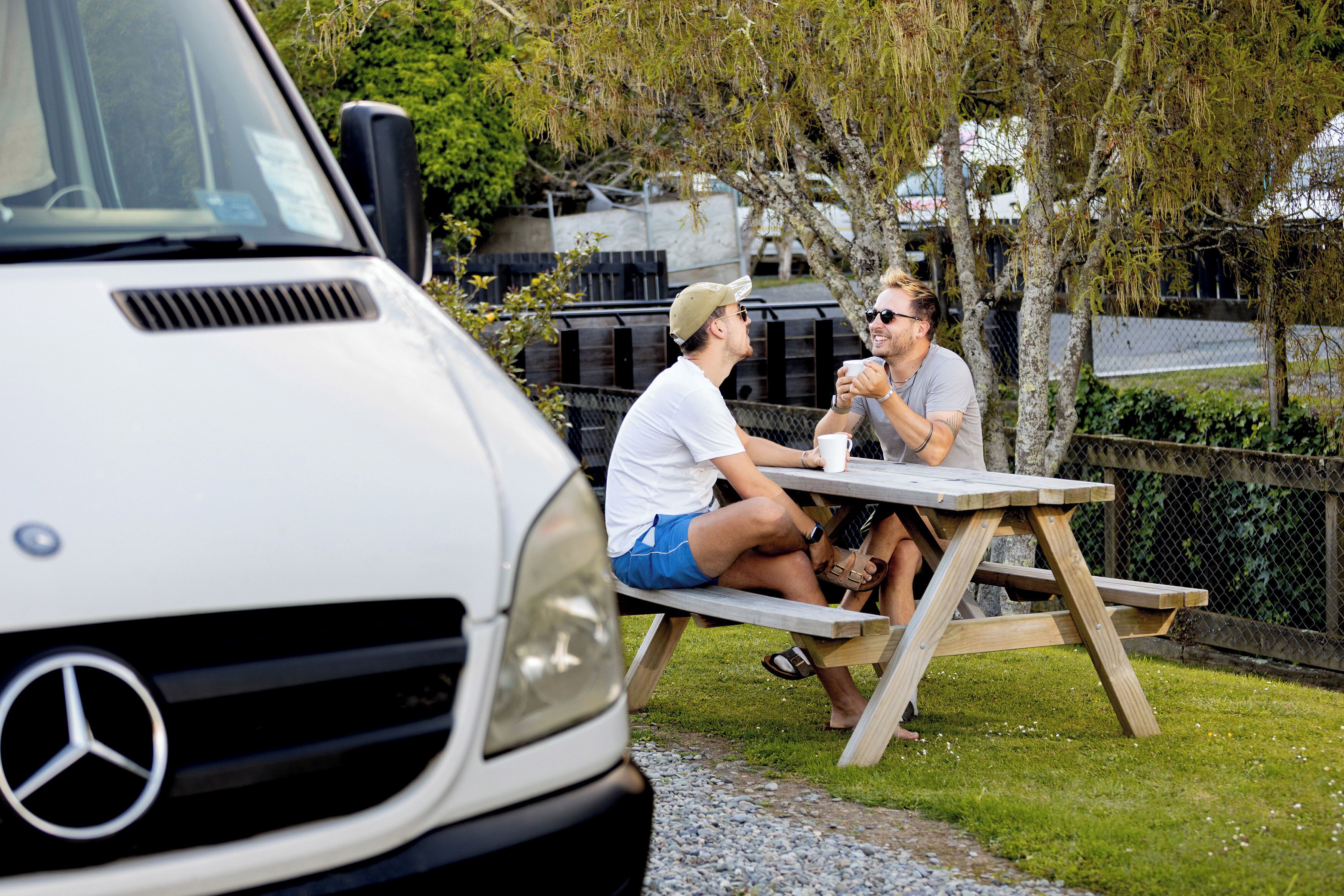 Two people sitting at a wooden picnic table outdoors.