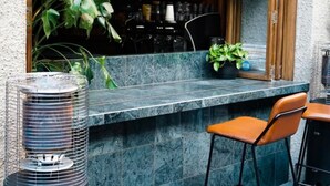 A bar with a sign reading "Malt & Juniper" and a counter with chairs. - Eminence on Bank (Adelaide)