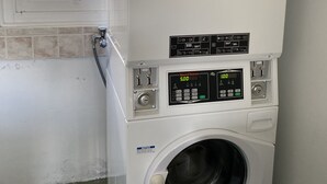 Un appareil combiné lave-linge et sèche-linge, avec un panneau de commande, une fenêtre au-dessus du sèche-linge et un sol carrelé.
