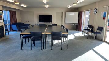 Un salón de conferencias con una gran mesa y sillas, una televisión, una pizarra y un reloj en la pared.