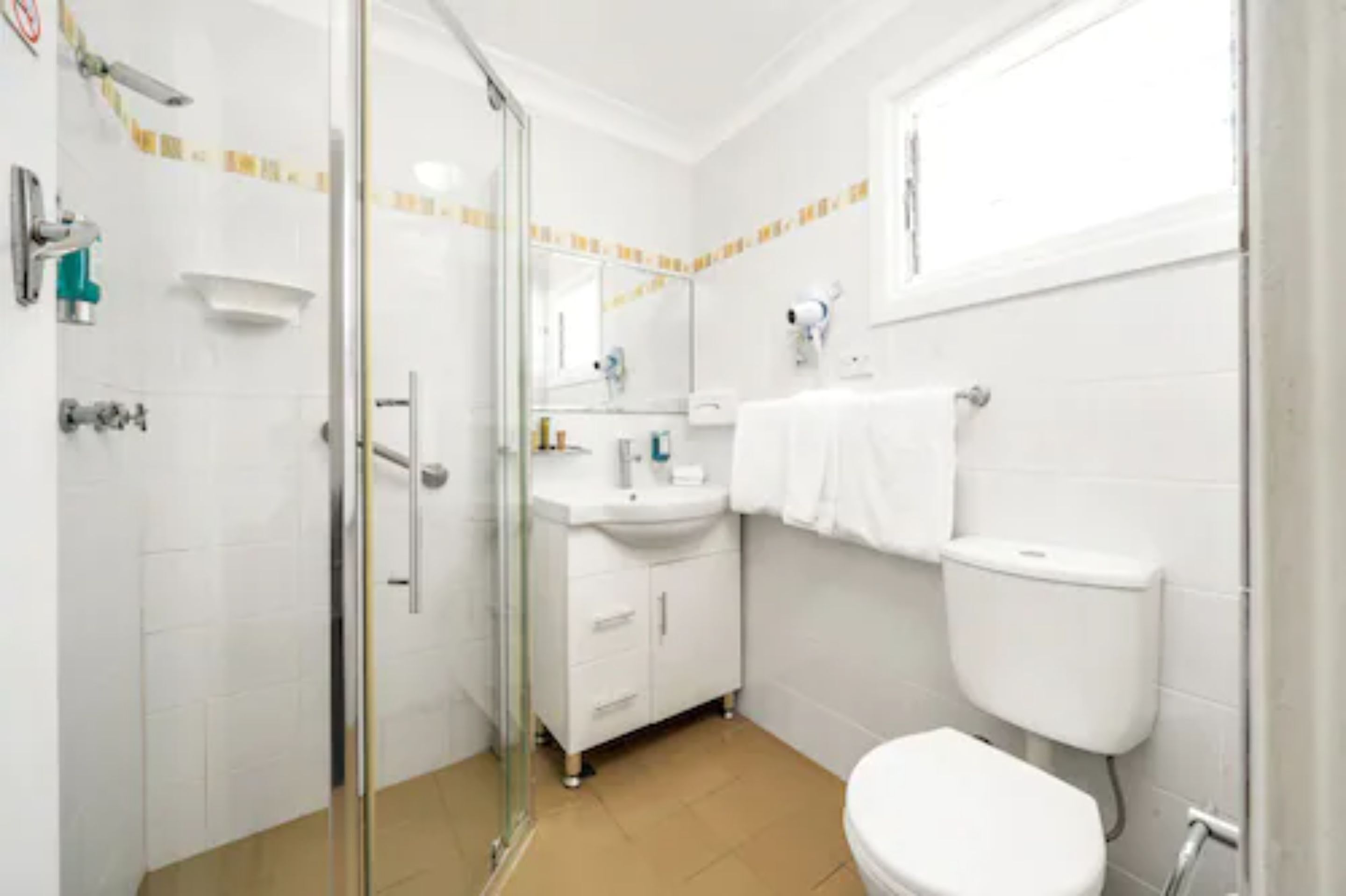 A bathroom with a glass shower enclosure, a white sink, a toilet, and a mirror.