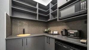 A modern kitchen with grey cabinets, a microwave, a coffee machine, and a sink. - Kiama Motel 617 (Kiama)