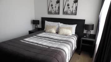 A neatly made bed with a striped bedspread, two pillows, and two bedside tables with lamps.